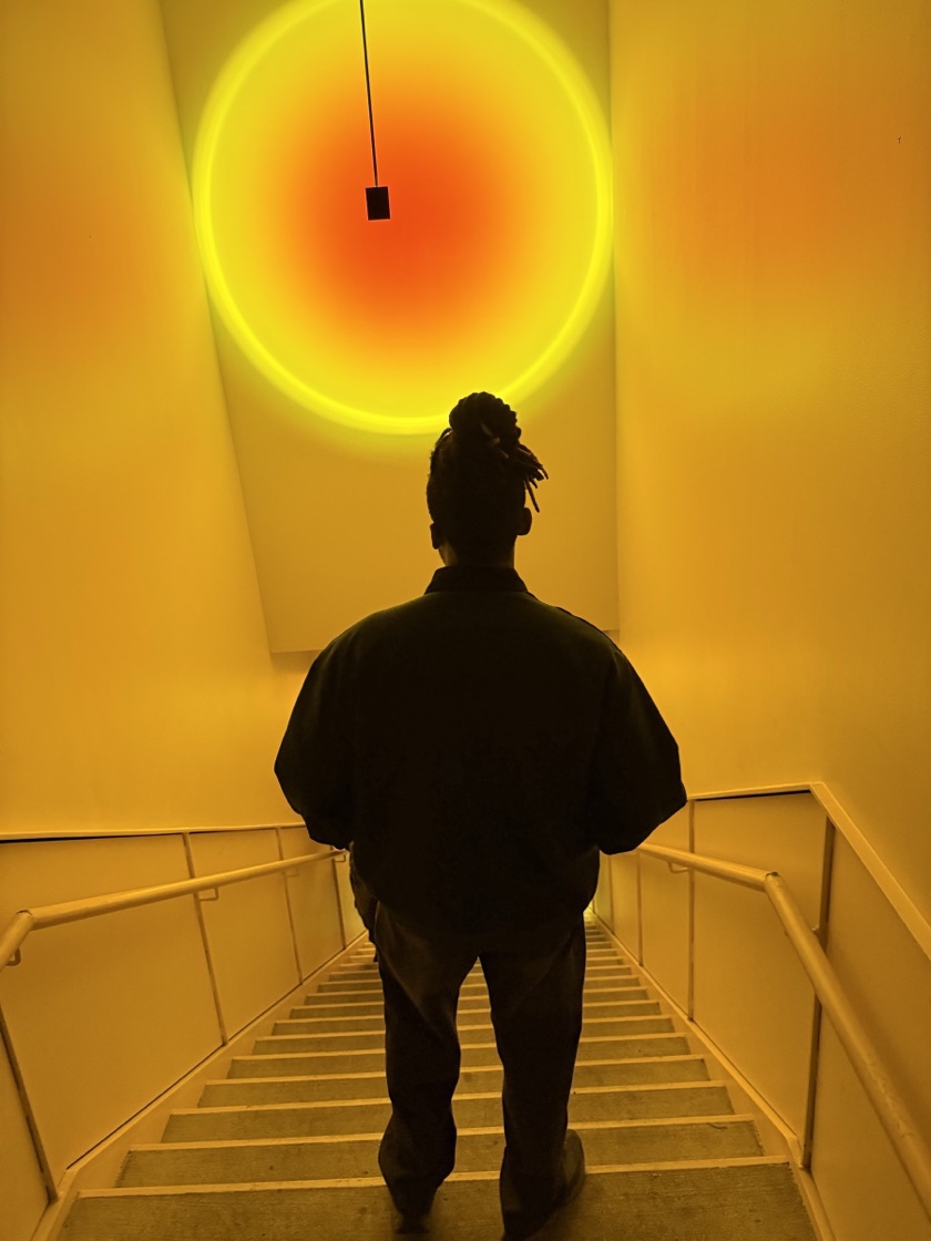 Ike, seen from behind on a stairwell under a glowing circle of light.